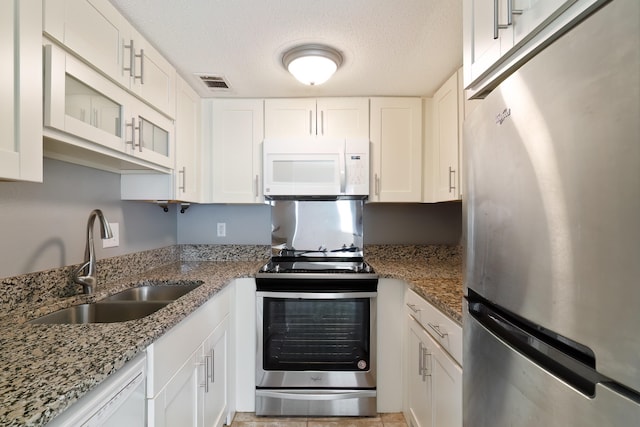 kitchen with stone counters, white cabinets, sink, a textured ceiling, and stainless steel appliances