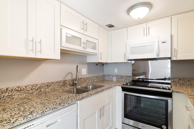 kitchen with light stone countertops, sink, white cabinets, and white appliances