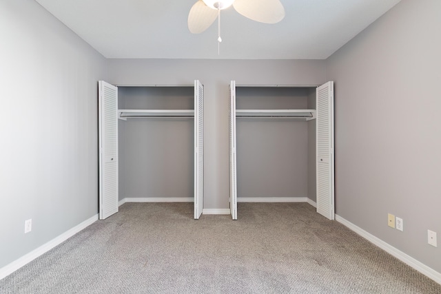 unfurnished bedroom with carpet, ceiling fan, and two closets