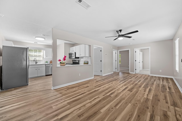 unfurnished living room featuring ceiling fan, sink, and light hardwood / wood-style flooring