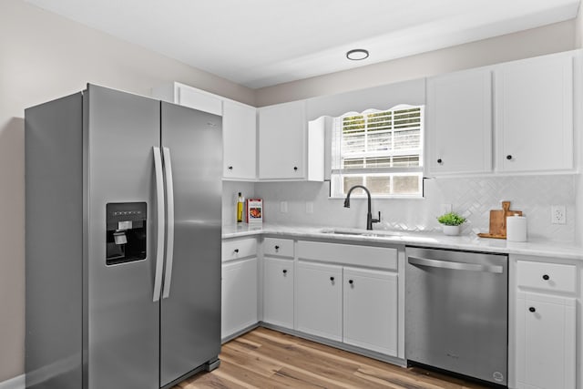 kitchen featuring appliances with stainless steel finishes, light wood-type flooring, white cabinetry, and sink