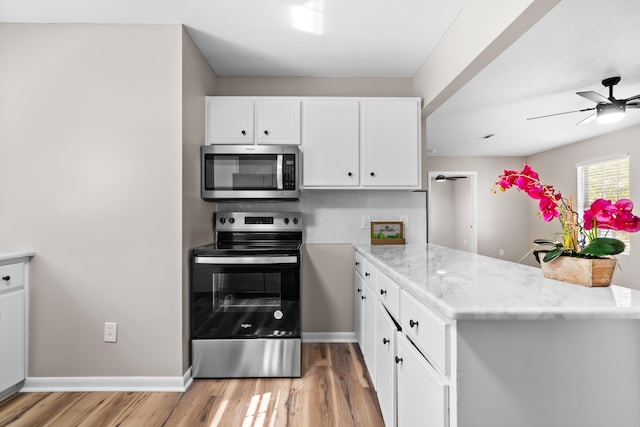 kitchen with light stone counters, white cabinetry, kitchen peninsula, and appliances with stainless steel finishes