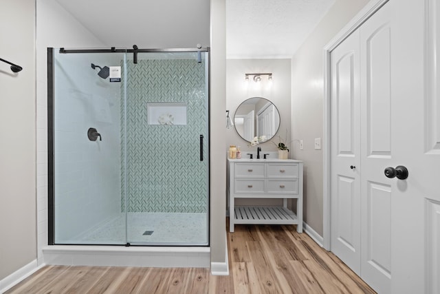 bathroom with wood-type flooring, vanity, a textured ceiling, and walk in shower