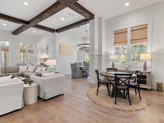 living room with beamed ceiling, an inviting chandelier, coffered ceiling, and light hardwood / wood-style flooring