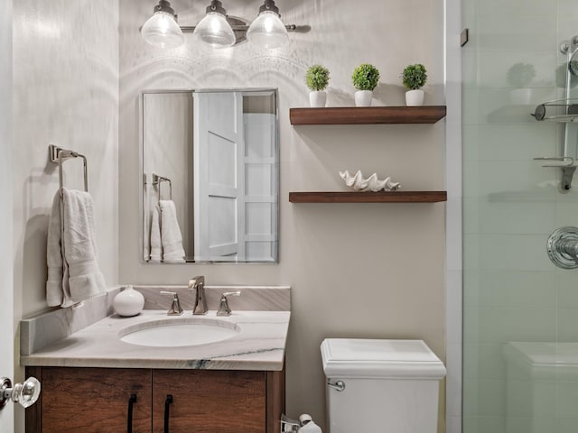 bathroom featuring vanity, toilet, and a shower with door