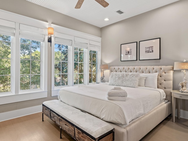 bedroom with ceiling fan, multiple windows, and light hardwood / wood-style flooring