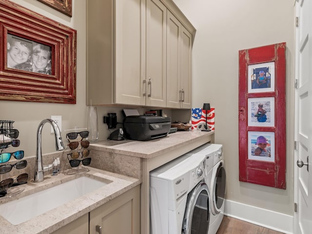 clothes washing area featuring separate washer and dryer, cabinets, sink, and wood-type flooring