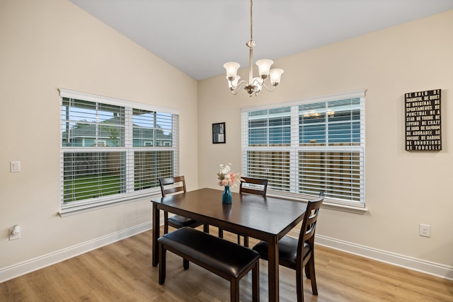 dining space with a chandelier, light hardwood / wood-style floors, and lofted ceiling