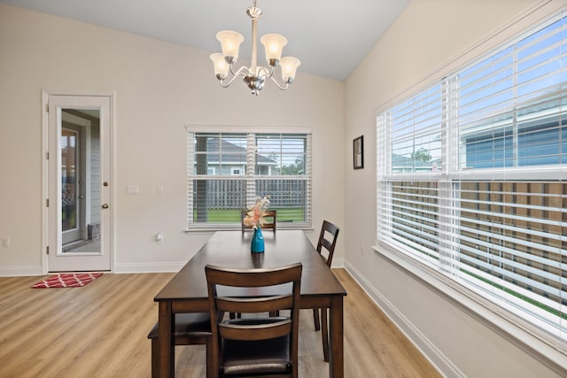 dining room with light hardwood / wood-style floors, lofted ceiling, and a notable chandelier