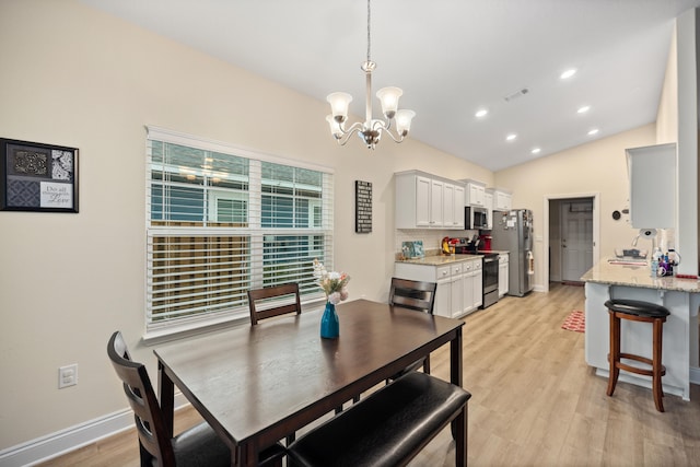 dining room with light hardwood / wood-style floors, lofted ceiling, and a notable chandelier