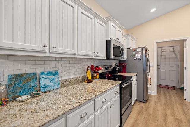 kitchen with decorative backsplash, light stone counters, stainless steel appliances, light hardwood / wood-style flooring, and white cabinetry