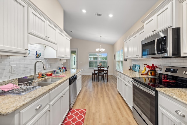 kitchen with lofted ceiling, white cabinets, decorative light fixtures, and appliances with stainless steel finishes