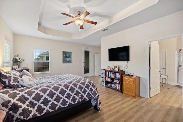 bedroom featuring ceiling fan, a tray ceiling, and light hardwood / wood-style flooring