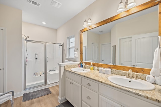 bathroom featuring hardwood / wood-style flooring, vanity, and a shower with door