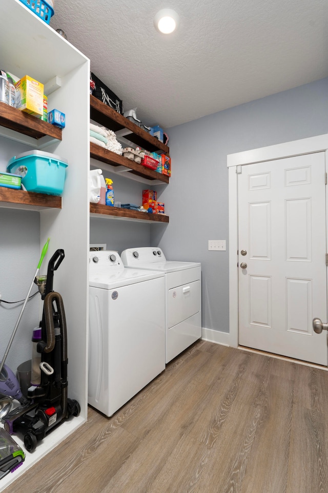 clothes washing area with washer and clothes dryer and light hardwood / wood-style floors