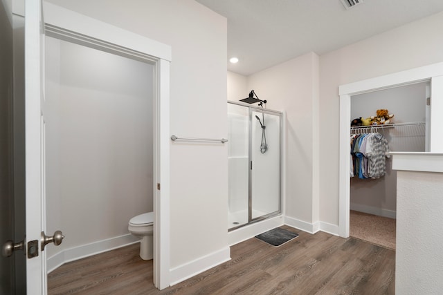 bathroom featuring hardwood / wood-style flooring, toilet, and a shower with shower door