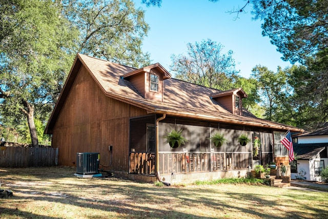 view of side of home featuring a sunroom, cooling unit, and a lawn