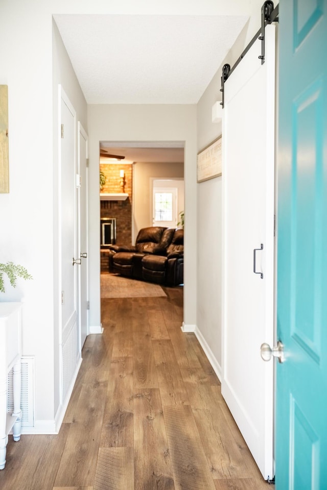 hall with a barn door and light hardwood / wood-style flooring