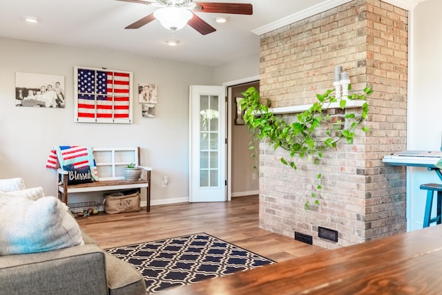 sitting room with hardwood / wood-style flooring, ceiling fan, and crown molding