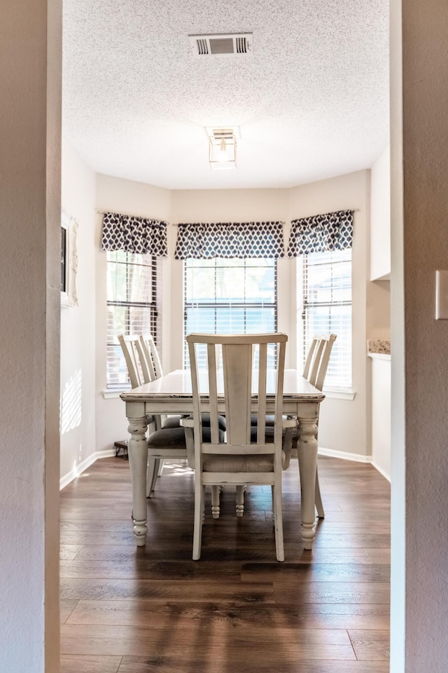 dining space featuring a textured ceiling, plenty of natural light, and dark hardwood / wood-style floors