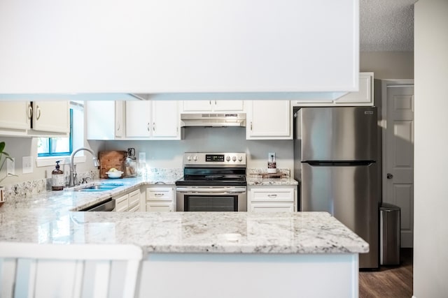 kitchen featuring sink, appliances with stainless steel finishes, white cabinetry, light stone counters, and kitchen peninsula