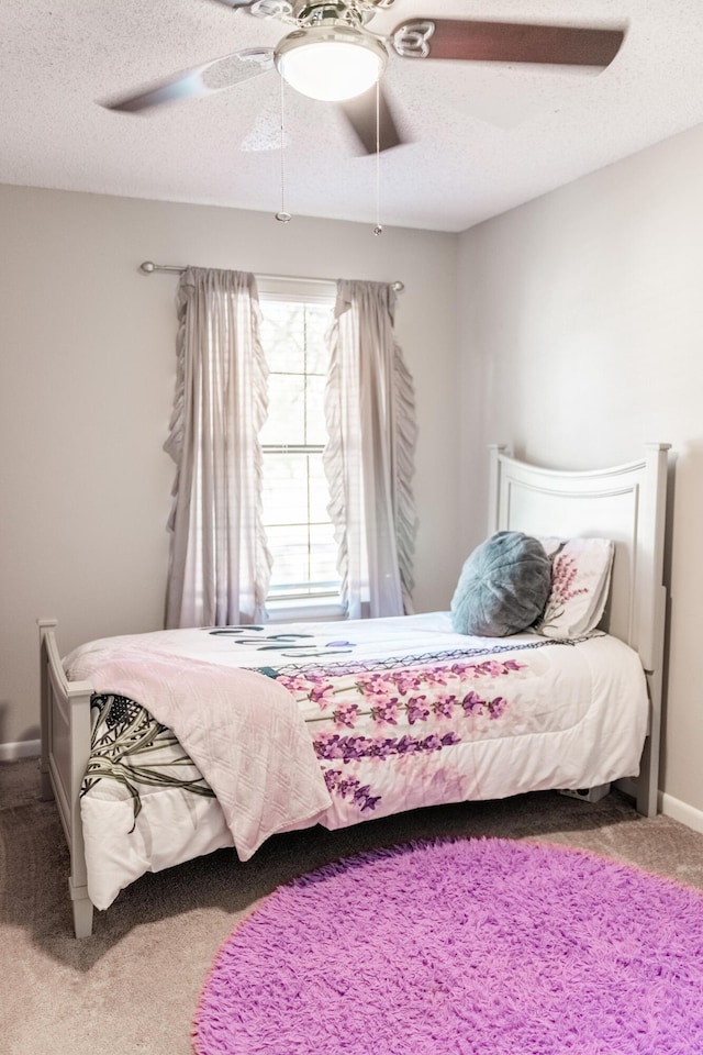 carpeted bedroom with ceiling fan and a textured ceiling