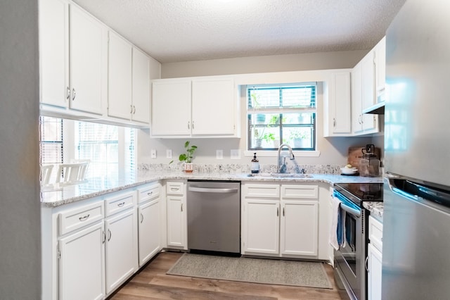 kitchen with sink, white cabinets, stainless steel appliances, and a textured ceiling