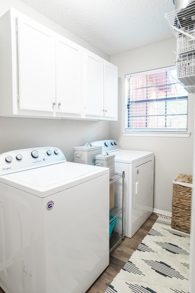 laundry room featuring hardwood / wood-style flooring, cabinets, a textured ceiling, and washing machine and clothes dryer