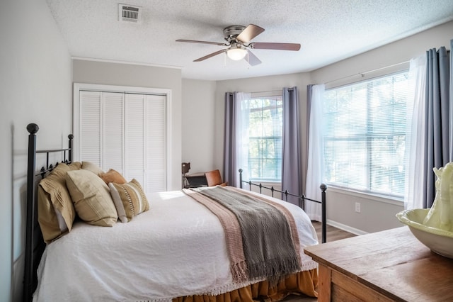 bedroom featuring multiple windows, ceiling fan, and a closet