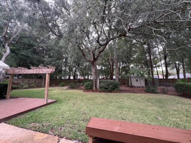 view of yard with a fenced backyard, an outdoor structure, a deck, and a shed