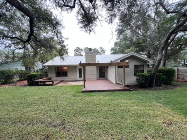 back of house featuring a chimney, fence, a lawn, and a patio