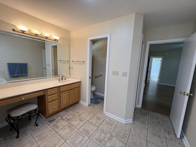 bathroom with baseboards, toilet, tile patterned floors, a textured ceiling, and vanity