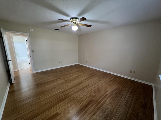 spare room with dark wood-type flooring, visible vents, and baseboards