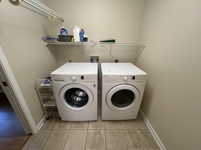 clothes washing area with laundry area, light tile patterned floors, baseboards, and separate washer and dryer