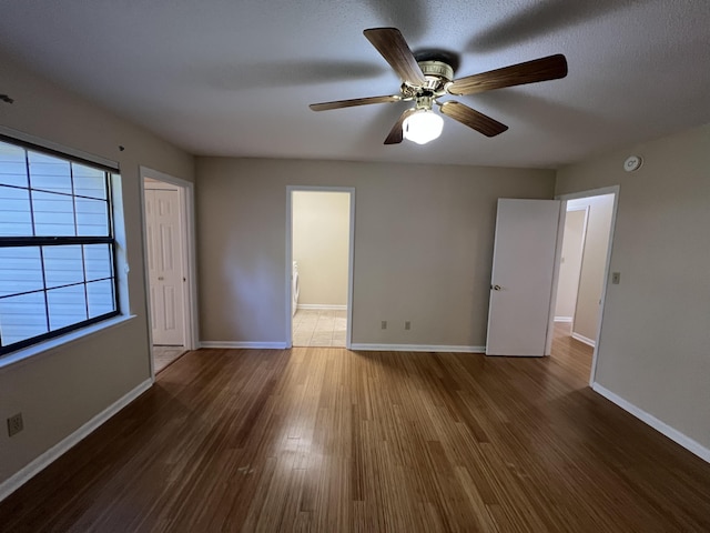 spare room with dark wood finished floors, baseboards, and ceiling fan