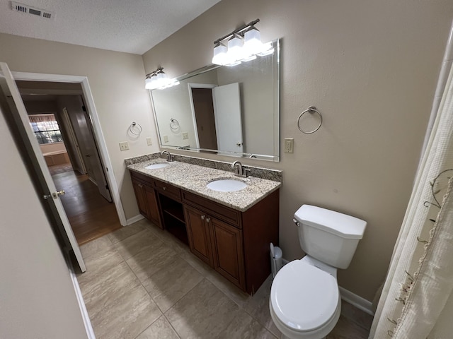 bathroom with visible vents, a sink, a textured ceiling, and double vanity