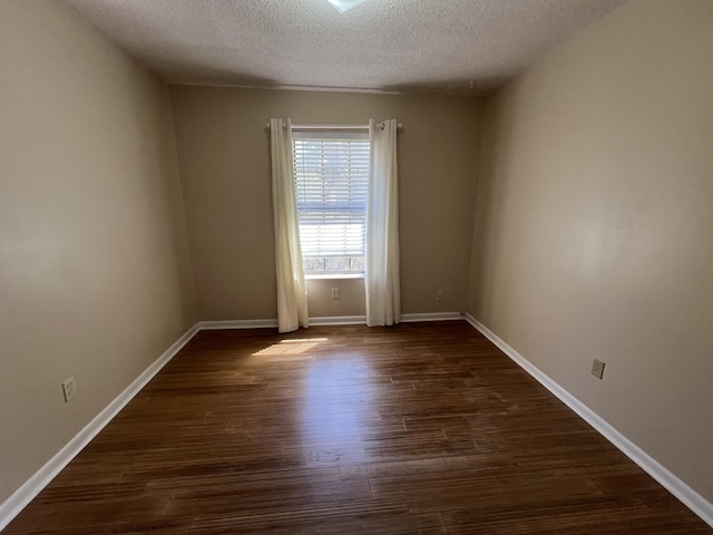 empty room featuring dark wood-style flooring, a textured ceiling, and baseboards