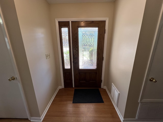 foyer with baseboards, visible vents, and wood finished floors