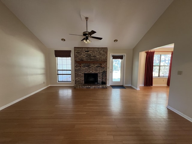 unfurnished living room with a fireplace, a ceiling fan, wood finished floors, high vaulted ceiling, and baseboards