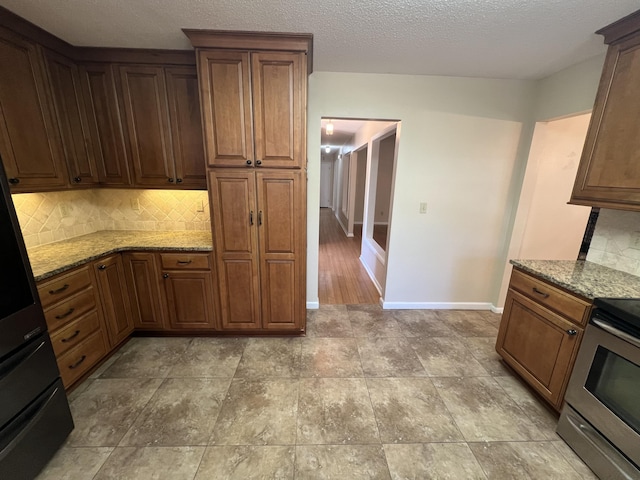 kitchen featuring light stone counters, backsplash, electric range, and baseboards