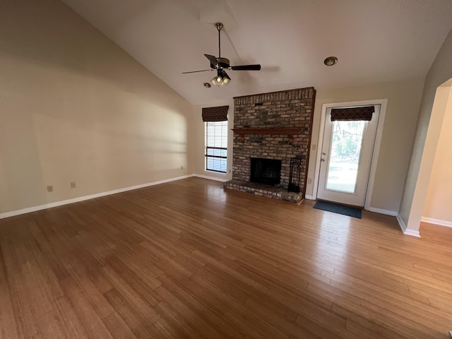 unfurnished living room with ceiling fan, high vaulted ceiling, wood finished floors, baseboards, and a brick fireplace