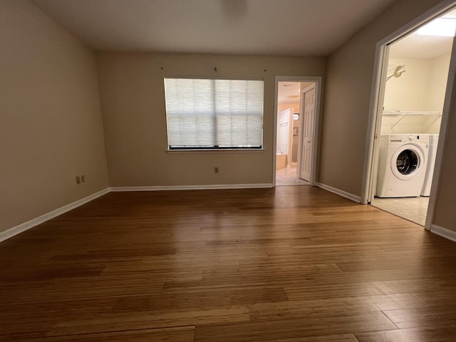 laundry area with wood finished floors, washer / clothes dryer, baseboards, and laundry area