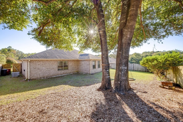 rear view of property with a yard and central air condition unit