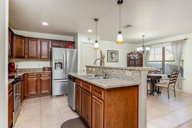 kitchen with pendant lighting, sink, appliances with stainless steel finishes, an island with sink, and light tile patterned flooring