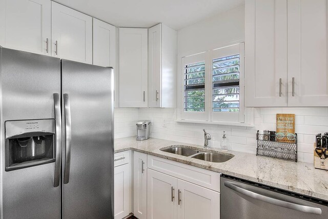 kitchen featuring decorative backsplash, appliances with stainless steel finishes, light stone countertops, sink, and white cabinets