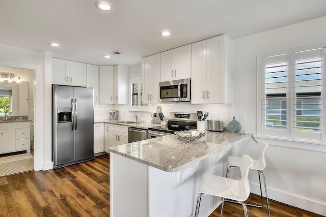 kitchen with appliances with stainless steel finishes, dark hardwood / wood-style flooring, and white cabinetry