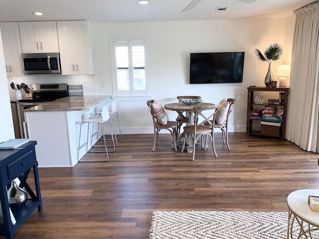 kitchen featuring white cabinets, stainless steel appliances, kitchen peninsula, and dark wood-type flooring