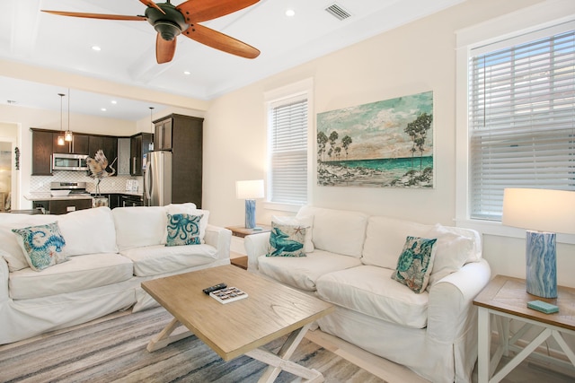 living room with ceiling fan, crown molding, beamed ceiling, and light hardwood / wood-style floors