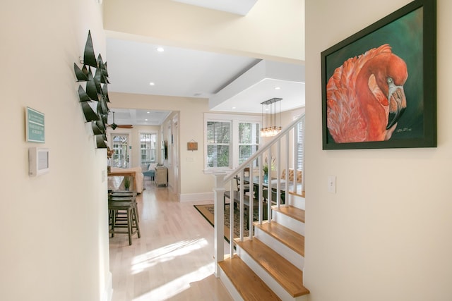 stairway with ceiling fan with notable chandelier and hardwood / wood-style flooring