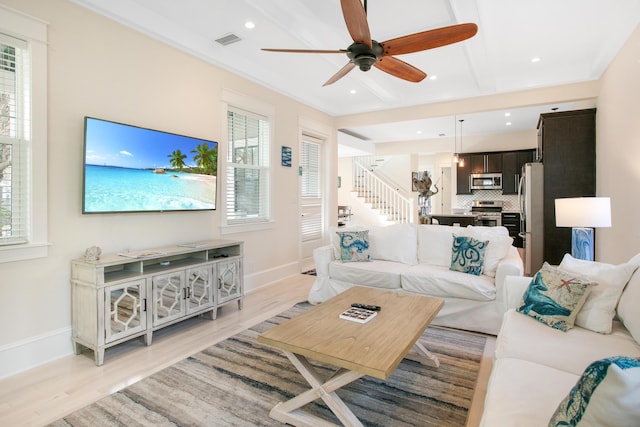 living room featuring ceiling fan, light wood-type flooring, and ornamental molding